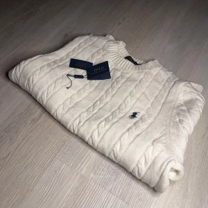 Vit stickad tröja från Ralph Lauren - Säljer en oanvänd och stilren stickad tröja från Polo Ralph Lauren. Tröjan är i storlek M och är köpt för cirka 1800kr, väldigt goo till våren