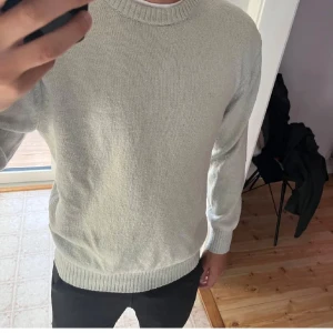  stickad tröja från H&M - Säljer en ljusgrå stickad tröja från H&M med relaxed fit. Tröjan har rund halsringning, långa ärmar och ribbade muddar vid ärmslut och nederkant. Perfekt för lager-på-lager under kyligare dagar.