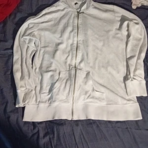 Vit hoodie med dragkedja från Tippy - Säljer en vit hoodie från Tippy i storlek XL. Tröjan har dragkedja framtill, huva och två fickor. Perfekt för en avslappnad stil och enkel att matcha med det mesta. Materialet känns mjukt och bekvämt.