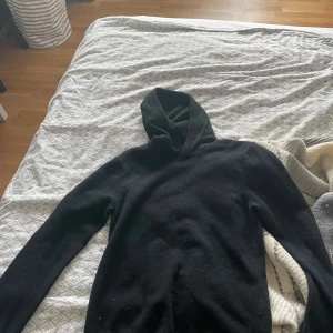 Svart hoodie från Vaillent i merinoull - Säljer en svart hoodie från Vaillent i mjuk merinoull. Tröjan har lång ärm och klassisk huva, perfekt för dig som gillar stilrena och bekväma plagg. Passar dig som vill ha en enkel och tidlös look. Hör av dig vid minsta fundering!