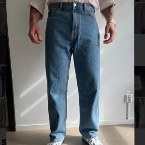 Blå Weekday Galaxy Loose Straight jeans - Säljer ett par klassiska blå jeans från Weekday, modell Galaxy Loose Straight. Jeansen har en rak och loose passform och fem fickor. Perfekta för en avslappnad stil och passar till det mesta.