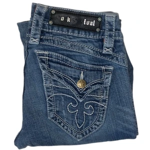 Rock Revival jeans - Lågmidjade Bootcut Rock Revival jeans. W28. Fläckar (bild 3/4) utbytt knapp på högra fickan. Uppsydda. [Ytterbenslängd 99cm] [Innerbenslängd 77cm] [Midja 37cm] [Benöppning 21cm]