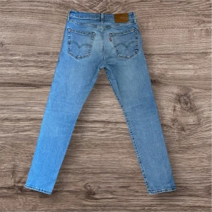 Levis 512 ljusblå jeans - Ljusblå Levis 512 jeans med klassisk femficksdesign och raka ben. Jeansen har en hög midja och är tillverkade i denim med en lätt tvättad look. Perfekta för en avslappnad stil och passar till det mesta. Hör av dig vid frågor eller prisförslag!