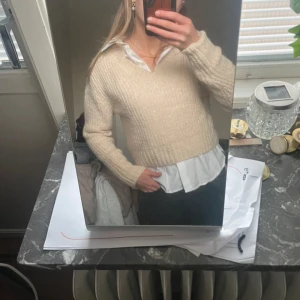 Beige stickad tröja från Monki - Säljer en beige stickad croppad tröja från Monki med v-ringning och långa ärmar. Tröjan har en mjuk och mysig känsla, perfekt att styla med skjorta under eller bara som den är. Superenkel att matcha till olika outfits!💞💞