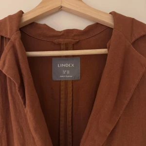 Brun kappa från Lindex - Säljer en snygg brun kappa från Lindex i storlek XS. Jackan har lång ärm, två fickor framtill och stängs med en knapp. Materialet känns lätt och passar perfekt till vår och höst.