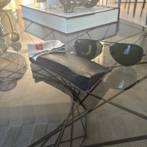 Ray-Ban  solglasögon - Klassiska Ray-Ban solglasögon med pilotbågar i svart metall och mörkgröna glas. Kommer med originalfodral i svart läderimitation och putsduk. Perfekt accessoar för en cool och tidlös stil.