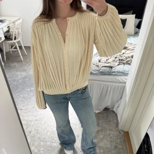 Beige kofta  - Säljer en beige ribbad kofta från Anne Bruse. Koftan har långa ärmar och ett mjukt, stickat material som ger en avslappnad men stilren look. Mycket fint skick! 