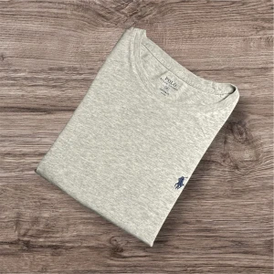 Ralph Lauren T-Shirt – Grå (S)  - Ralph Lauren T-Shirt – Grå (S) 🩶  Säljer en snygg och stilren grå t-shirt från Ralph Lauren. Perfekt basplagg i mjukt och bekvämt material – funkar lika bra till vardags som under en skjorta eller jacka. 	•	Färg: Grå 	•	Storlek: S (baserat på måtten) 	•	Mått: 📏 Längd 67 cm, armhåla till armhåla 51 cm, axel till axel 42 cm 	•	Nypris: ca 1800 kr 💸 	•	Skick: Billigt pris p.g.a. defekten på sista bilderna – syns knappt när tröjan används.  110