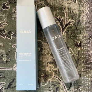 CAIA SOS Rescue Glowing Oil Mist - Fräsch ansiktsmist från CAIA i en genomskinlig flaska med vit kork. SOS Rescue Glowing Oil Mist ger glow och återfuktar huden. Passar alla hudtyper och innehåller närande oljor. Helt ny men kartongen är lite trasig