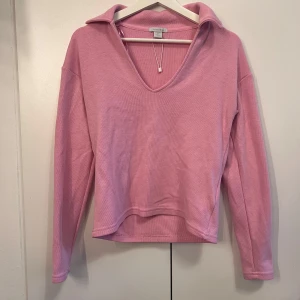 Rosa långärmad tröja med krage  - Den söt rosa långärmad tröja från newyorker. Tröjan har en djup v-ringning och en bred krage.