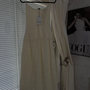 Krämvit ärmlös klänning från Zara - Superfin krämvit klänning från Zara i storlek M. Klänningen är ärmlös med en lätt strukturerad yta och har en v-ringad hals. Perfekt för varma dagar och enkel att styla med accessoarer.