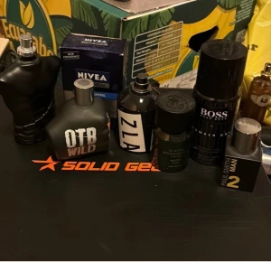 Blandade herrparfymer från olika märken - Samling med herrparfymer: Jean Paul Gaultier Le Male (svart kropp), OTB Wild (matt grå flaska), Zlatan Ibrahimovic Myth Wood (mörkgrön), Hugo Boss Number One (svart randig), Paul Smith Man 2 (svart/gul). Flera flaskor i unika former och färger.