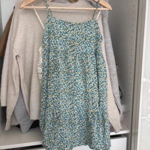 Blommig sommarklänning från Zara - Supersöt blommig klänning från Zara i storlek S. Klänningen har smala axelband, ärmlös design och ett blått och grönt blommönster på ljus botten. Perfekt för varma dagar och enkel att styla med sneakers eller sandaler. 💕