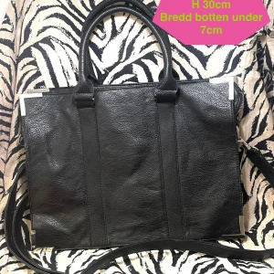 Äkta Gina Tricot axelväska/crossbody  - En snygg, stylish och rymlig handväska/axelväska/ crossbodyväska i äkta retro/ vintage anda från ca år 2000. Själva modellen heter Carro bag, men ni finner all info på lappen i väskans foder. Den är i gott skick förutom några väldigt små ställen där materialet släppt men jag har foto på alla så ni kan se hur det ser ut. Väskan har både handtag att hålla i och ett reglerbart axelband som är avtagbart. Fina detaljer i metall på väskans hörn. Mått; L 40cm H 30cm Bredd på botten 7cm 