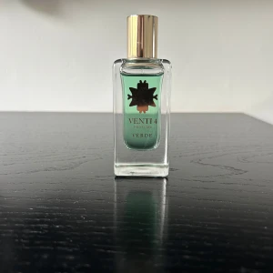 Venti4 Verde Eau de Parfum - Fräsch parfym från Venti4 med grön vätska i en stilren, rektangulär glasflaska. Flaskan har en guldfärgad kork och en dekorativ svart logotyp på framsidan. Doften heter Verde och passar dig som gillar gröna, fräscha toner.
