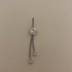Silver navelpiercing - Snyggt silverfärgat navelpiercing smycke med en rund glittrande sten upptill och två hängande kedjor med små stenar längst ut. Stilren och modern design som ger en elegant touch till din look. Jätte fin nu i sommar. Använd 1 gång!