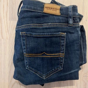 Mörkblå jeans från Denim & Supply - Snygga mörkblå jeans från Denim & Supply Ralph Lauren med klassisk femficksdesign och kontrastsömmar. Jeansen har raka ben och är tillverkade i slitstarkt denimtyg. Perfekta för dig som gillar en tidlös och clean look. midja 38-39 stretch längd 102 benöppning 15 inseam 80