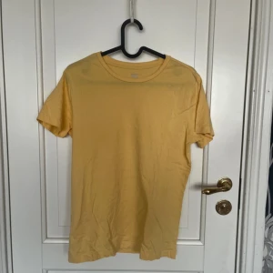 Gul t-shirt från 157, storlek S - En basic gul t-shirt från 157 i storlek S. Tillverkad i 100% ekologisk bomull med klassisk rund hals och korta ärmar. Perfekt för dig som gillar en enkel och clean stil med en poppig färg. Sitter normalt och är superbekväm till vardags.