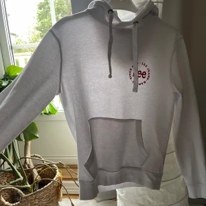 Vit hoodie från Lee Jeans med tryck - Vit hoodie från Lee Jeans med rött tryck på bröstet. Klassisk känguruficka framtill, snörning i huvan och mjukt material. Perfekt för en chill och avslappnad stil. Långärmad och med bekväm passform.