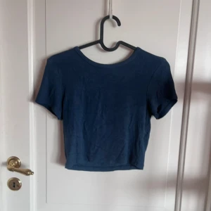 Mörkblå croppad topp från Zara - Enkel och stilren mörkblå croppad topp från Zara med rund halsringning och korta ärmar. Perfekt till jeans eller kjol för en chill look. Mjuk och skön bomullskänsla, passar dig som gillar basic men snyggt.