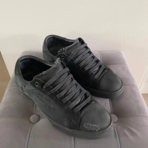 Svarta Saint Laurent sneakers - Svarta sneakers från Saint Laurent med slitna detaljer och grova kanter för en edgy look. Skorna har breda svarta snören, rund tå och platt sula. Materialmix av canvas och skinn med Saint Laurent-logga på sidan och tungan. Dem är storlek 40.5 men passar 41 och bra skick! Inget OG tillkommer! (Slitningarna är med i modellen så är inte defekter)