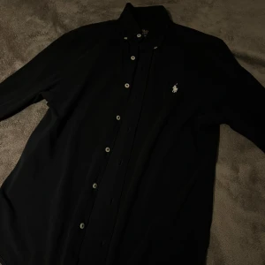 Ralph Lauren skjorta - Eftertraktad  långärmad skjorta från Polo Ralph Lauren i lätt bomullsmaterial. Klassisk krage, vita knappar och ikonisk broderad logga på bröstet. Snygg och stilren modell som passar perfekt till jeans eller chinos.