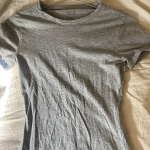 Grå t-shirt från Intimissimi  - En basic grå t-shirt från Intimissimi i mjuk Supima-bomull. Modellen är klassisk med rund halsringning och korta ärmar. Perfekt för en clean och enkel stil, lätt att matcha med allt. Snygg passform och superbekväm att bära.