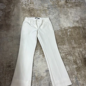 Vita kostymbyxor från Bik Bok - Vita kostymbyxor från Bik Bok . Byxorna har hällor för bälte, diskreta bakfickor och stängs med dragkedja och hake. Storlek 34