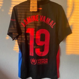 FC Barcelona x Cactus Jack – Lamine Yamal #19 (S) - Säljer en ny och oanvänd matchtröja från det unika samarbetet mellan Barcelona och Cactus Jack (Travis Scott). 🔥tagg finns och går att scanna 📏 Storlek: S 💯 Tryck: Lamine Yamal #19 + UNHCR-logga ✔️ Svart design med röd/blå detaljer – limited edition!  Skickas snabbt. Skriv vid intresse!