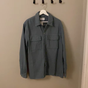 Overshirt - Säljer denna schyssta Overshirt! Den är typ khakifärgad, lite toner av blått och grått. Helt ny med lapp kvar, köpt på vinted för 250 spänn, nypris 35 euro! Storleken som står är M men det går mot en large skulle jag säga. Riktigt go nu till sommaren! Skriv om du har frågor✌️
