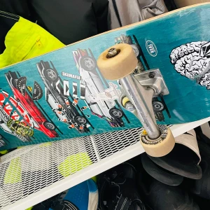 Skateboard - ny skick - Bilden visar en skateboard med färgglada dekaler och motiv, men ingen bok syns. Om du letar efter en bokbeskrivning, vänligen ladda upp en bild på en bok.