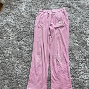 Rosa Juicy Couture mjukisbyxor - Supermjuka rosa mjukisbyxor från Juicy Couture. Stor logga på fickan där fram. Har blivit smutsiga och slitna på vissa ställen som man ser på bild 3,4 och 5. Säljer pågrund av att de har blivit för korta för mig. Finns inte lapp med storlek kvar men de är i storlek 10/11 år.