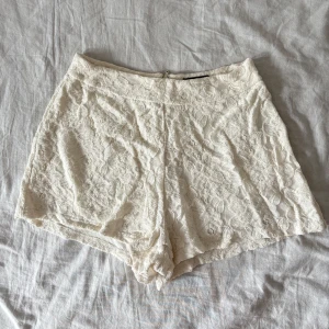 Vita spets-shorts från Bik Bok - Superfina vita shorts från Bik Bok i spets med blommigt mönster. De är högmidjade och har dragkedja bak för en clean look. Perfekta till sommaren när du vill ha något ljust och fräscht. Snygg passform och mjukt innerfoder för extra komfort.