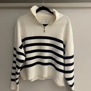 Stickad tröja - Säljer en ribbstickad tröja från MNG i vitt med svarta horisontella ränder. Tröjan har hög krage och half zip-dragkedja framtill. Långärmad och i en lite loose passform, perfekt för lager på lager. Materialet är mjukt och känns riktigt cozy.
