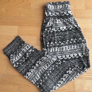 Mörkblå och vita harembyxor med grafiskt mönster - Mörkblå och vita byxor med grafiskt mönster och bred, hög midja. Byxorna är i mjukt material och har muddar vid bensluten. 