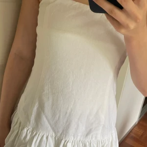 Tajt off shoulder klänning  - Vit tajt kortklänning från Pull&Bear med volangig kjol. Klänningen har en dragkedja på sidan, den har även blivit uppsydd för en tajtare passform så den passar xxs och har aldrig använts 