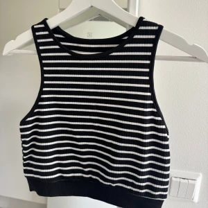 Svartvit randig ribbad linnetopp - Säljer en croppad linnetopp med svarta och vita horisontella ränder. Toppen är ribbad och ärmlös med rund halsringning 🌸