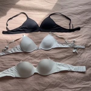 Svart och vita bandeau toppar - Tre stilrena bandeau toppar i svart och vitt, perfekta att bära under skjortor eller som de är. Två av topparna är vita, varav en är axelbandslös och en har justerbara axelband. Den svarta toppen har tunna axelband. Alla är mjuka och bekväma.