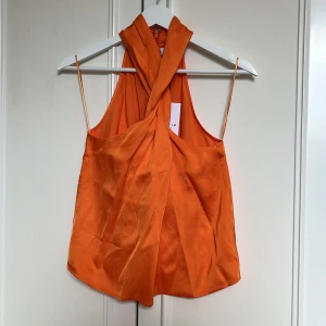 Orange omlott blus med halterneck - Orange blus från STOCKHOLM LM STUDIO omlottmodell med halterneck. Helt oanvänd, prislapp kvar!