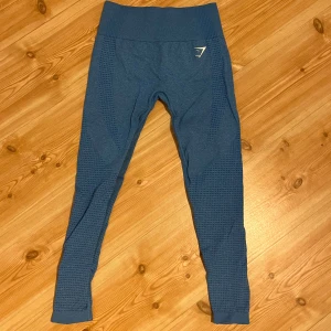 Blå seamless leggings från Gymshark - Snygga blå leggings från Gymshark med seamless design och diskret mönstrad struktur längs benen. Hög midja för extra komfort och stöd, perfekt för gymmet eller andra träningspass. 