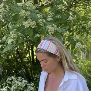 Randigt hårband från Djerf Avenue - Säljer ett hårband  från Djerf Avenue hårbandet har färgglada ränder i rosa, blått, gult och vitt. Perfekt accessoar för att lyfta vilken outfit som helst med en lekfull touch.