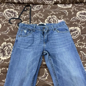 Levi's 511 Slim blå jeans - Säljer ett par Levi's 511 Slim jeans i klassisk blå tvätt. Jeansen har fem fickor, gul kontrastsöm och en liten distressed detalj vid fickan. Modellen är slim fit med rak siluett och normal midja. Perfekt för dig som gillar en clean och tidlös look.