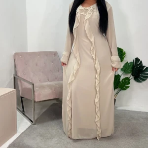 Beige långklänning med volang från Aavva -  beige långklänning från House of Haniya med volangdetaljer längs fram och runt halsen. Klänningen har långa ärmar med volang vid ärmslut och ett knytband i midjan för extra form. Klänningen är onesize men skulle säga att den passar från Xs-M kanske L då den går o knyta i midjan så mycket man själv vill. 