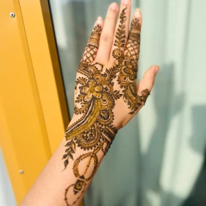 Ekologisk, naturligt Henna mehndi för hand, brun-svart  - Snyggt henna mehndi-mönster för hand med detaljerade blommor, blad och paisley i brun-svart färg. Designen är klassisk och täcker handryggen och fingrarna med tunna linjer och prickar. Perfekt för dig som vill ha en unik och konstnärlig look.