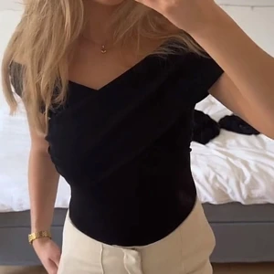 Svart omlott topp med v-ringning - Säljer en svart omlott topp med v-ringning och offshoulder-design. Toppen är tight och har en stilren, figurnära passform som framhäver siluetten. Perfekt att styla med både jeans och kjol för en trendig look.🤩🩷