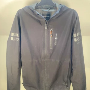 Sail racing jacka - Sail Racing dunjacka, storlek L. Vatten- och vindtät med stilren design. I bra skick men små grejer finns, kan skickas bild på, perfekt för kalla och blåsiga dagar. Funktionell och snygg. 💫