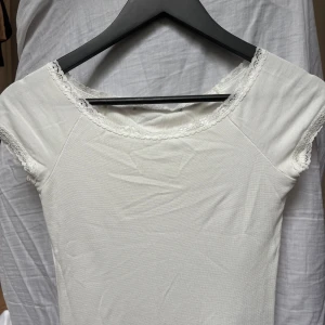 Vit spetskantad topp med kort ärm - Supersöt vit topp med korta ärmar och fina spetsdetaljer längs halsringning och vid ärmarna. Den är ifrån Lager 157 i storlek Xs. Kontakta om du har några funderingar!!❤️