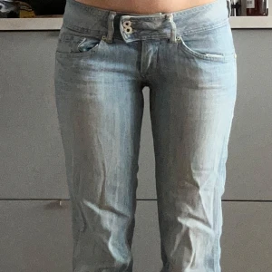 Ljusblå Pepe bootcut jeans - Säljer ett par ljusblå jeans från pepe jeans med rak passform och låg midja. De är klippta längst ner så de ska bli kortare. Midjemått rakt över 39cm, innerbenslängd 77cm. De har även ett litet hål under vänstra bakficka som inte märks när man har på sig dem. 