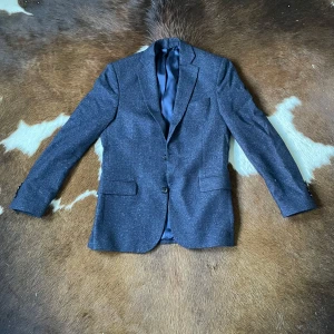 Mörkblå blazer från J.Lindeberg - Snygg mörkblå kavaj från J.Lindeberg med diskret prickigt mönster. Blazern är helt ny och aldrig  använd tyvär är prislappen borta. Men säljer pågrund av att den är för liten.Tveka inte på att höra av dig vid frågor!