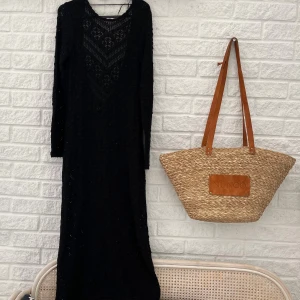 Svart lång stickad klänning - Säljer en svart lång stickad klänning med vackert virkat mönster.